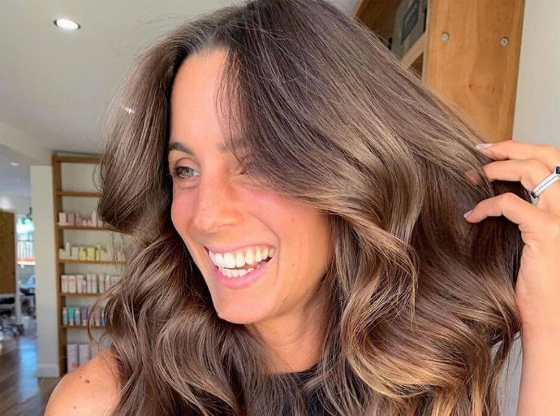 Une femme souriante avec ses cheveux volumineux 