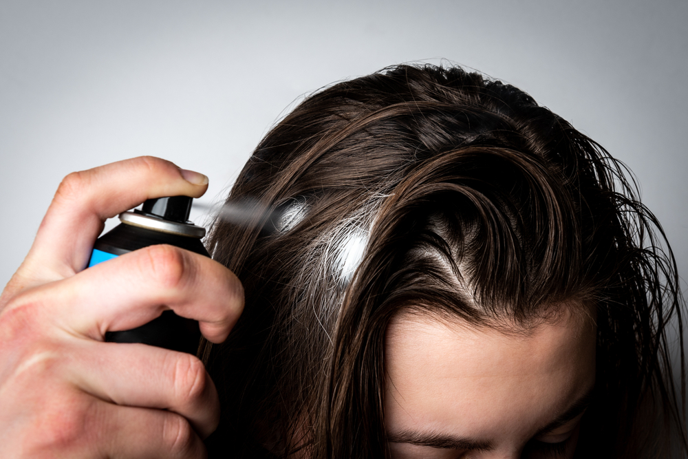 Traces blanches sur les cheveux d´une femme en utilisant shampoing sec