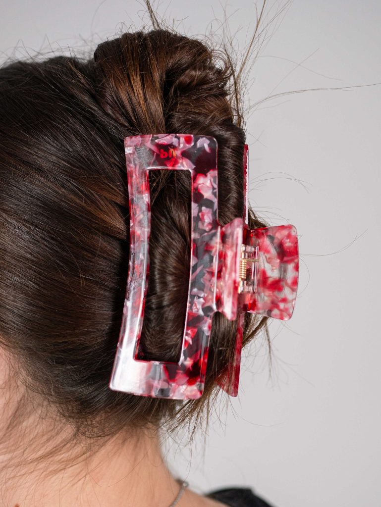 Pixie Woo claw clips in red, pink, and transparent that hold brown hair in place.




