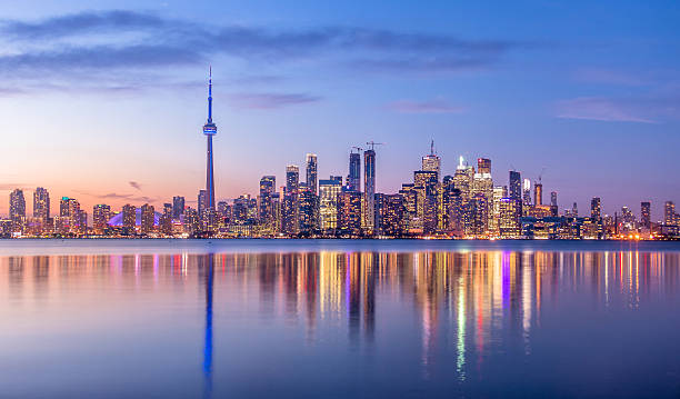 le centre ville de Toronto (cible incontournable des expatriés au Canada) avec une lumière violette. on y voit la Tour CN et de nombreux gratte-ciels autour. 