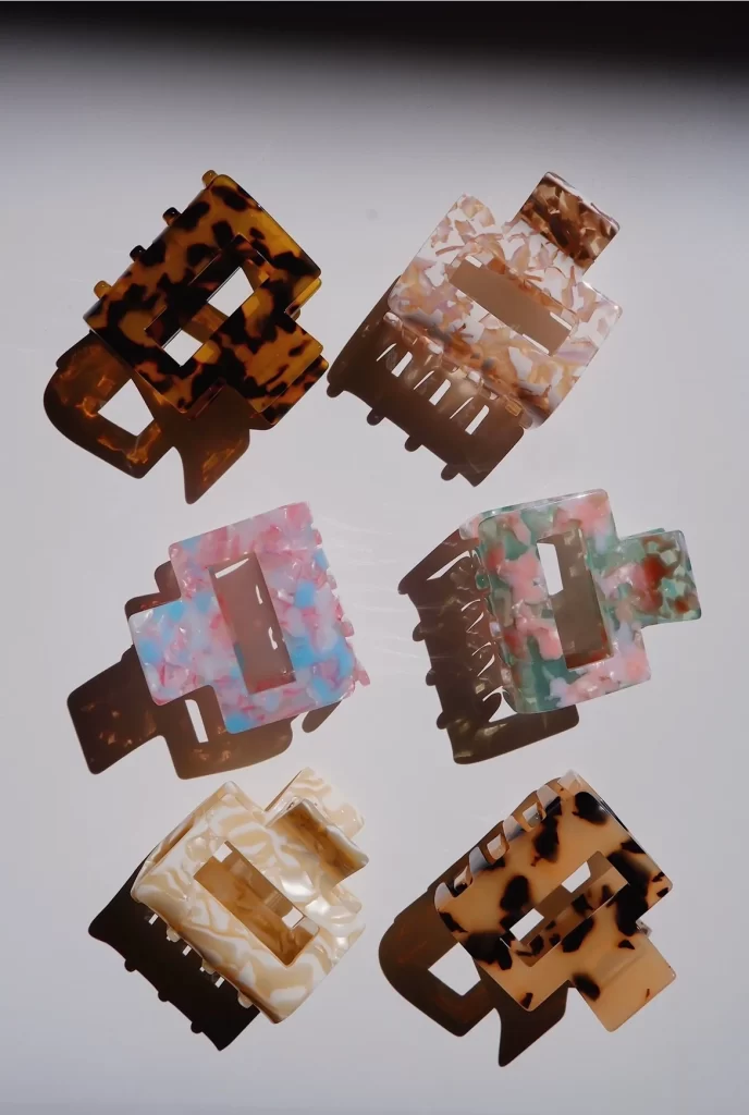 Six small-sized PixieWoo claw clips are visible. Clips of different colors can be seen, such as brown and black, pink and white, pink and blue, pink and green, beige and white, beige and brown.
