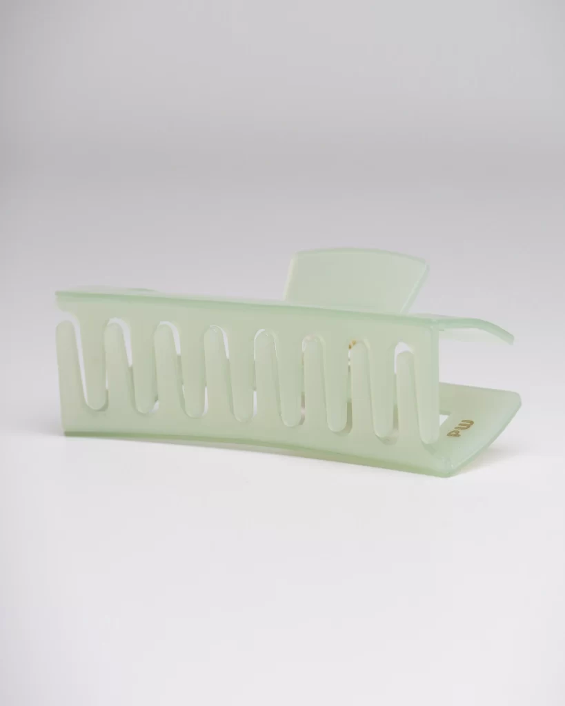 An image of a light green pixie woo hair clip (strongest hair clip). We also see the Pixie Woo logo in the hair clip. The hair clip is on a white background.

